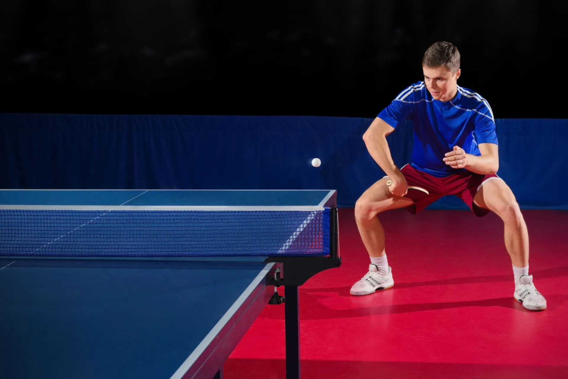 後陣からバックハンドを降る卓球選手